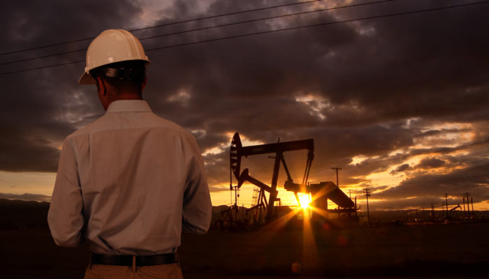 Engineer wearing hard hat helmet checking oil derrick field